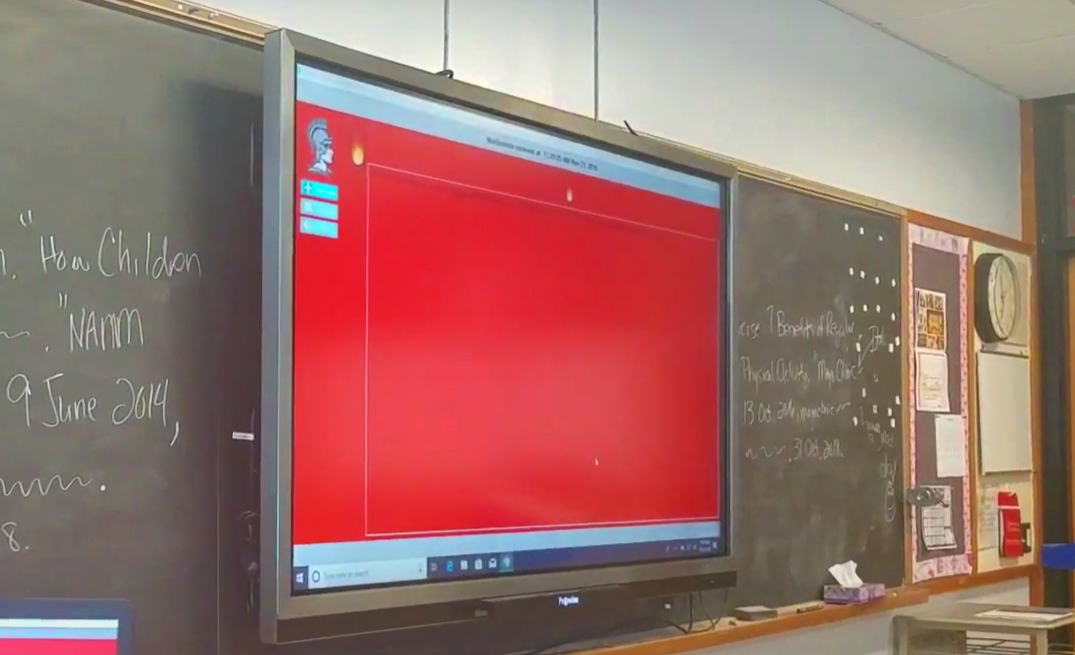 A smartboard in a classroom with emergency messaging