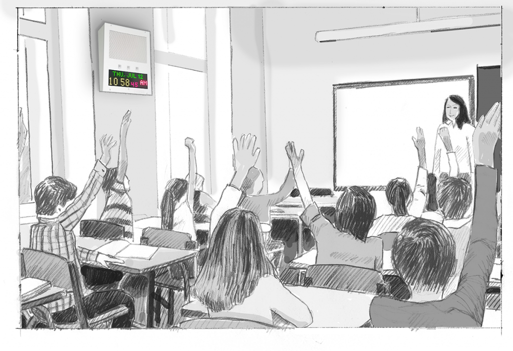 A teacher with elementary students in a classroom. An IP Speaker with Display on the wall shows the time.