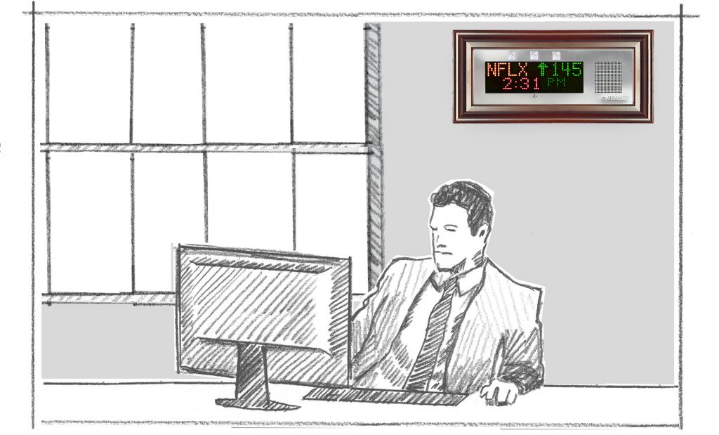 An employee in an office talks on the phone. A Small IP Display with wood frame on the wall scrolls a multi-color news feed.