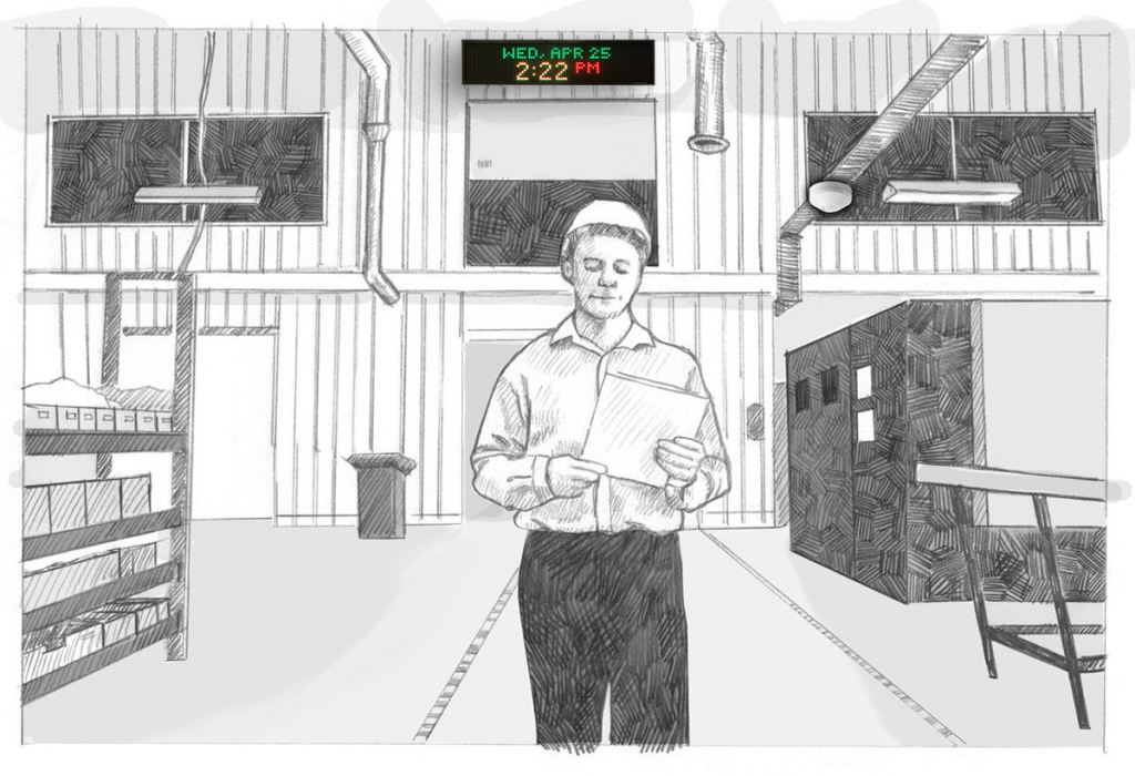 A worker in a hard hat walks through a warehouse. On the wall, the large Outdoor IP Sign shows the time and date.